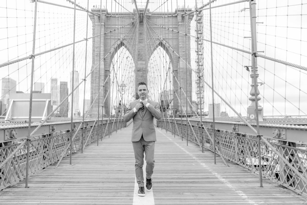 Groom walking brooklyn bridge by destination wedding photographer Julie Ferneau